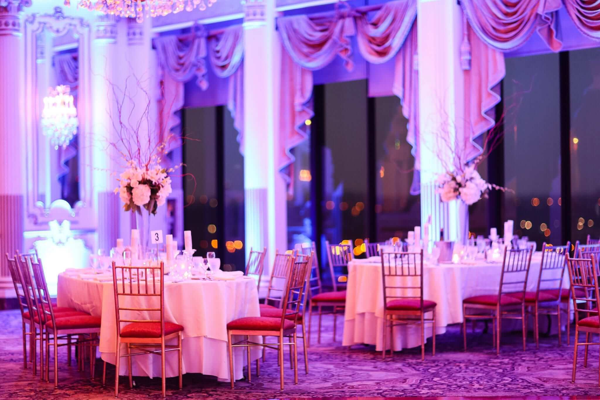 A large ballroom with tables and chairs set up for a wedding reception. Additional services include DJ services by bilingual New Jersey DJs.
