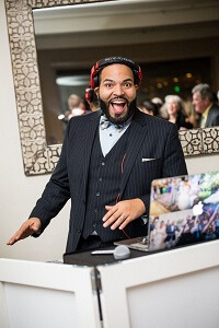 A bilingual man in a suit and tie is playing a DJ at a North New Jersey wedding.